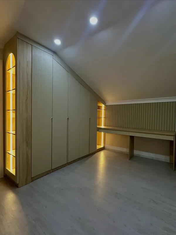 Çatı katı genç odası tasarımı - eğimli tavan altında çizgili lake kapaklar ve LED aydınlatmalı köşe nişler ile modern tasarım